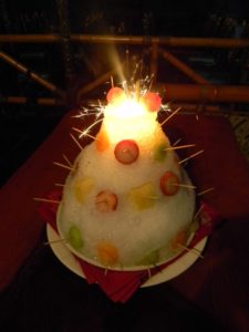 The Polynesian Surprise dessert adorned with fresh tropical fruits and set ablaze on table with sparklers.