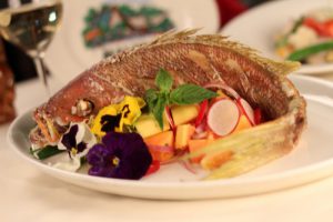 The colorful Crispy whole snapper over tropical fruit and garnished with orchid blooms.