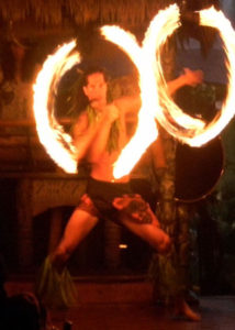 Male Polynesian fire dancer creating two simultaneous rings of fire with a dramatic flair.