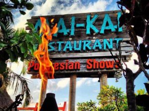 The dramatic tiki torch flames offset by the signature wooden Mai-Kai sign and blue sky.