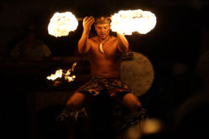 A solo fire dancer twirls a double ended fire torch as part of the Polynesian Islander Revue.